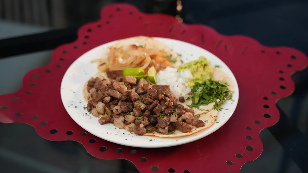 Tacos de Rib Eye — Cuatro tacos de rib eye finamente picado, con cebolla asada, guacamole, cilantro y limones.